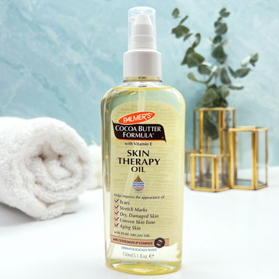 The best body oil for pregnancy, Palmer's Skin Therapy Oil on vanity with towels