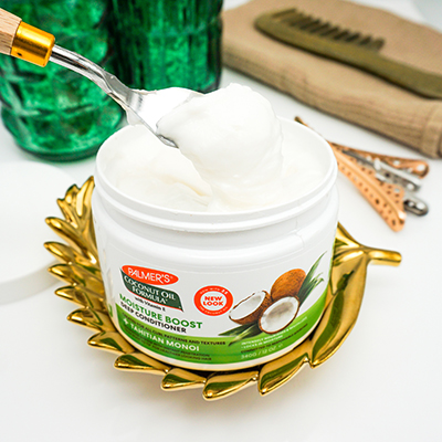 Palmer's Coconut Oil Formula Moisture Boost Deep Conditioner for healthy hair on table being scooped out of jar