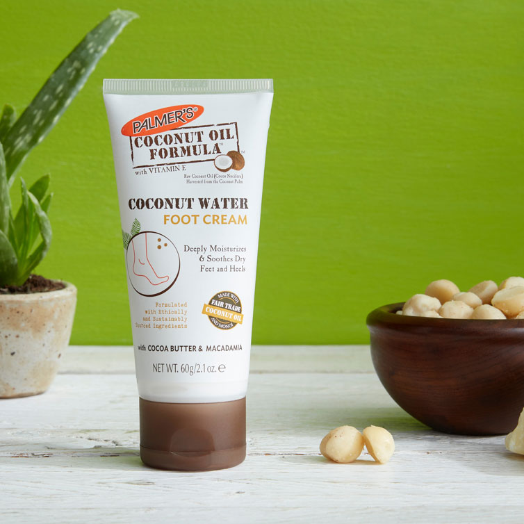 Palmer's Coconut Water Foot Cream, a coconut oil for feet product, on a table with macadamias