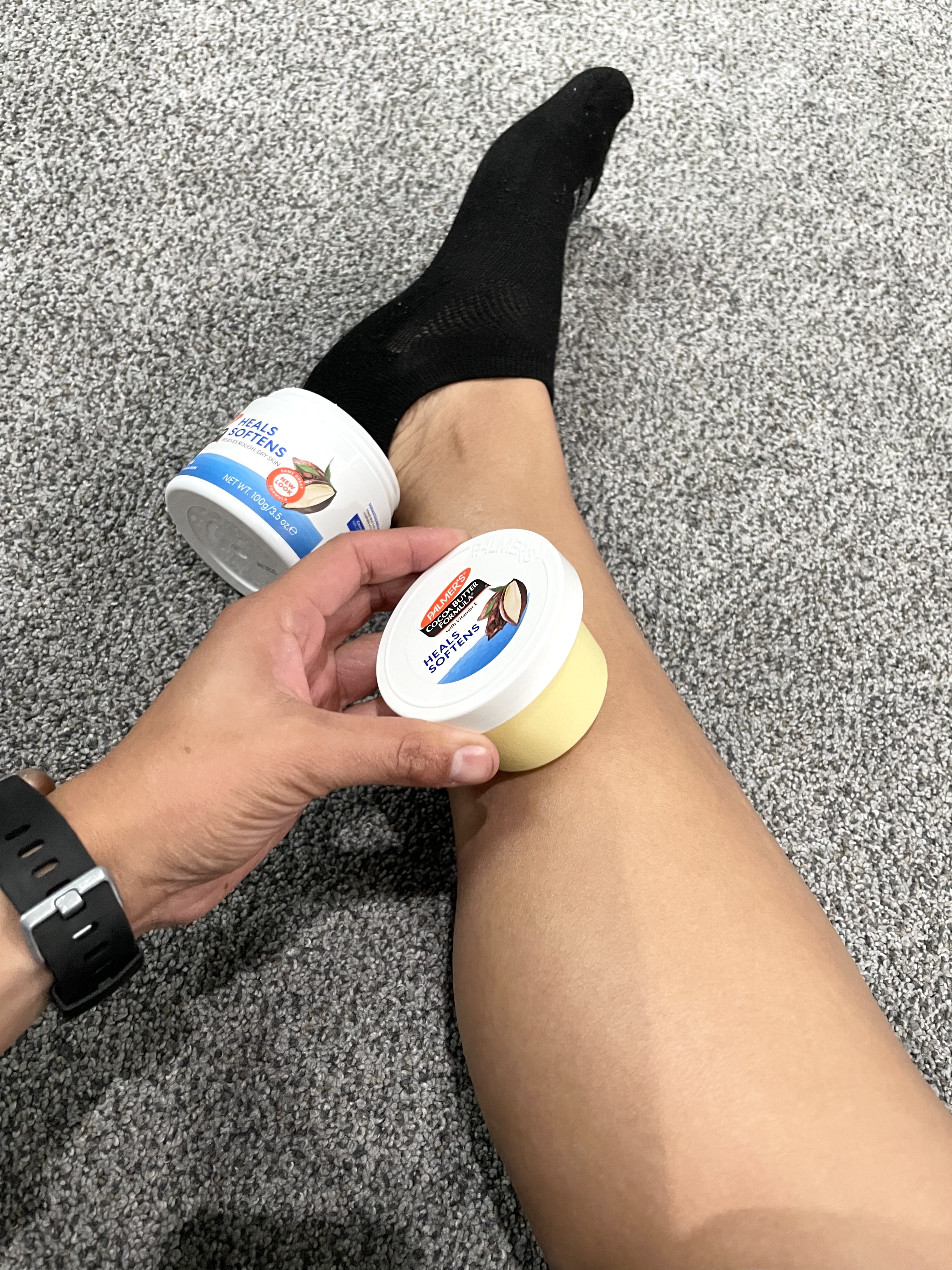 Woman applying dry skin solution, Palmer's Cocoa Butter Formula Original Solid Jar to her leg