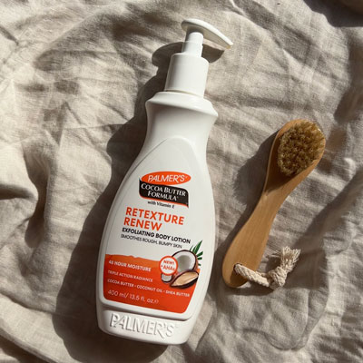 Palmer's Cocoa Butter Formula Retexture Renew Exfoliating Body Lotion on cloth with body brush
