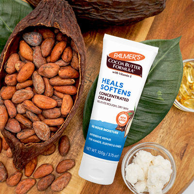 Palmer's Cocoa Butter Formula Concentrated Cream for extreme cold weather skin care on a table with cocoa beans and cocoa butter