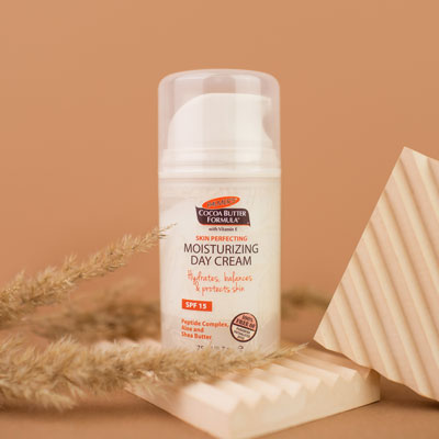 Palmer's Cocoa Butter Formula Moisturizing Day Cream, the perfect additional to your fall skincare routine, on table with ingredients