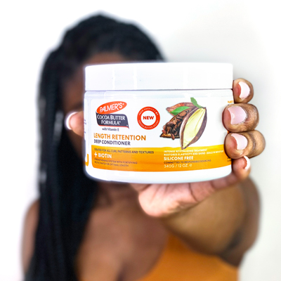 Palmer's Cocoa Butter Formula Length Retention Deep Conditioner, a moisturizer for all hair porosity levels, held by woman