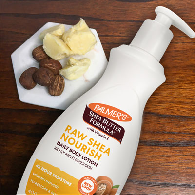 Palmer's Shea Formula Raw Shea Lotion on table with shea nuts and raw shea butter