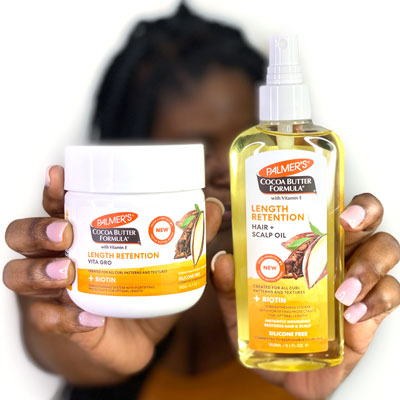 Black woman holding Palmer's Cocoa Butter Formula Length Retention for strengthening natural hair