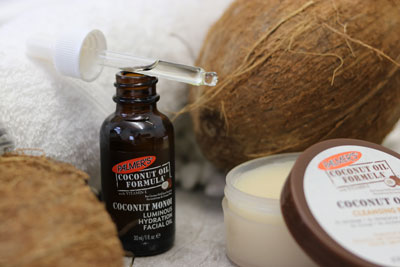 Palmer's Coconut Oil Facial Oil and Cleansing Balm, the best nighttime skin care routine for dry skin, on table with coconuts