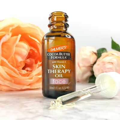 Palmer's Skin Therapy Face Oil, the best face oil for aging skin, bottle and dropper on table with flowers