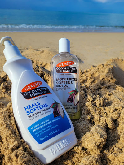Palmer's Cocoa Butter Body Oil vs Lotion on a beach  with woman's legs