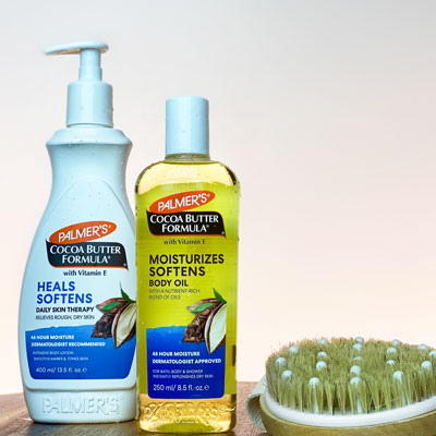 Palmer's Cocoa Butter Body Oil vs Lotion on table with dry brush