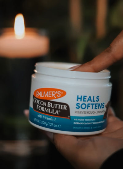 Woman's finger dipping into Palmer's Cocoa Butter Jar to use in a beauty hack during a spa day