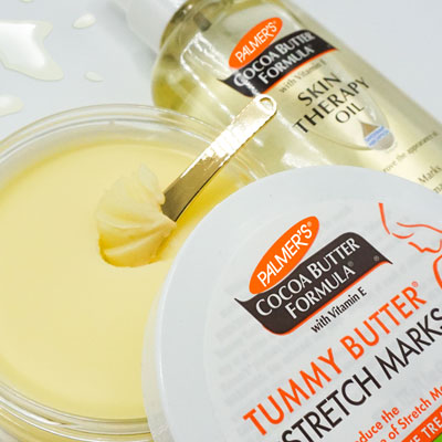 Closeup of open jar of Palmer's Tummy Butter for use during first trimester self care routines, with Skin Therapy Oil in background
