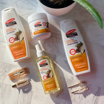 Palmer's Cocoa Butter Formula Length Retention products, ideal for low hair porosity, on table with hair accessories