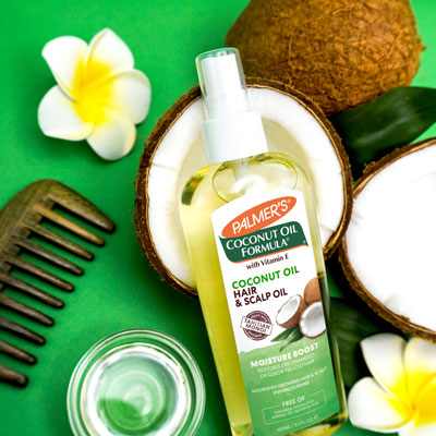 Palmer's Coconut Oil Hair & Scalp Oil for hair slugging in a coconut on a green background