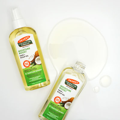 Palmer's Coconut Oil Formula Moisture Boost Hair and Scalp Oil for heat-damaged curls with oil spilled on table top