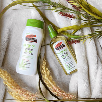 Palmer's Hemp Oil Calming Relief Body Lotion and Body Oil moisturizers for dry skin in winter on blanket with plants 