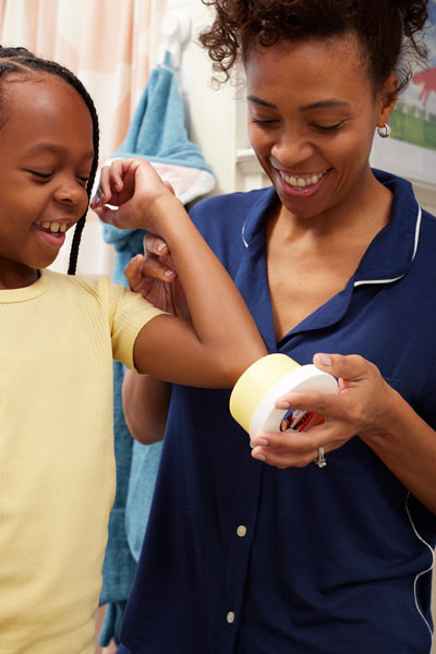 A mother and daughter applying Palmer's Cocoa Butter Formula Original Solid Jar during their self care routine