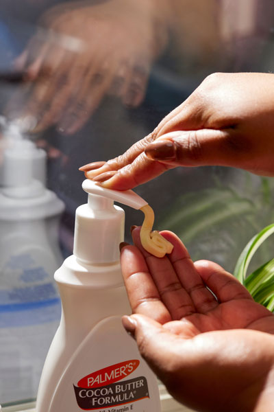 A woman's hands with Palmer's Cocoa Butter Formula Body Lotion during her selfcare routine