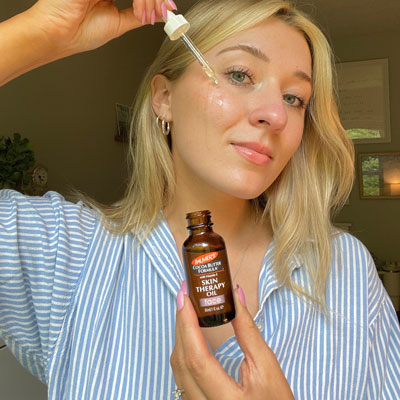 A caucasian woman applying key skin cycling product, Palmer's Skin Therapy Face Oil during her skin cycling routine