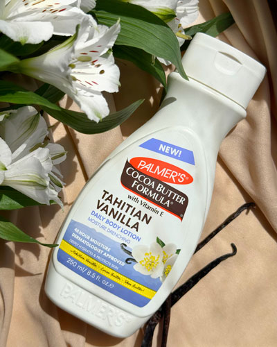 Palmer's Tahitian Vanilla Body Lotion on a wooden table with white flowers