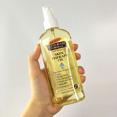 Palmer's Skin Therapy Oil, the best treatment for damaged skin, held in hand.