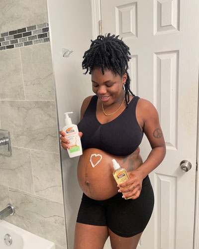 Pregnant woman applying Palmer's Massage Lotion and Skin Therapy Oil during third trimester pregnancy self care routine