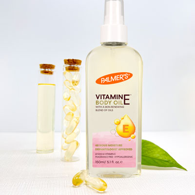 Palmer's Vitamin E Body Oil, a vitamin e for dry skin product, on a table with vitamin e capsules