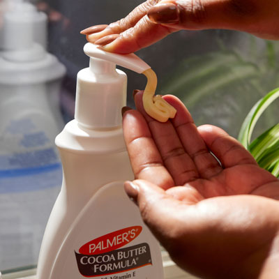 Woman's hand pumping out Palmer's Cocoa Butter Lotion, ideal for what to put on after shaving or waxing