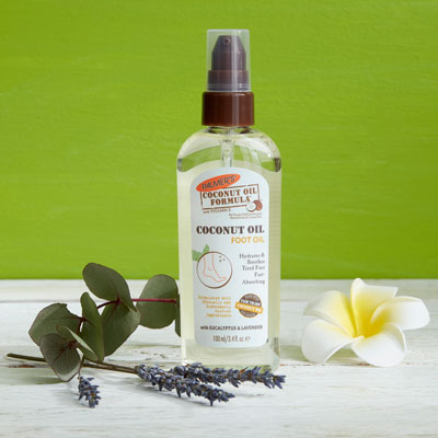 Palmer's Coconut Oil Foot Oil for winter foot care on a table with ingredients