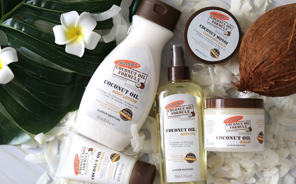 Palmer's Coconut Oil Formula skincare products on a table with coconuts and flowers