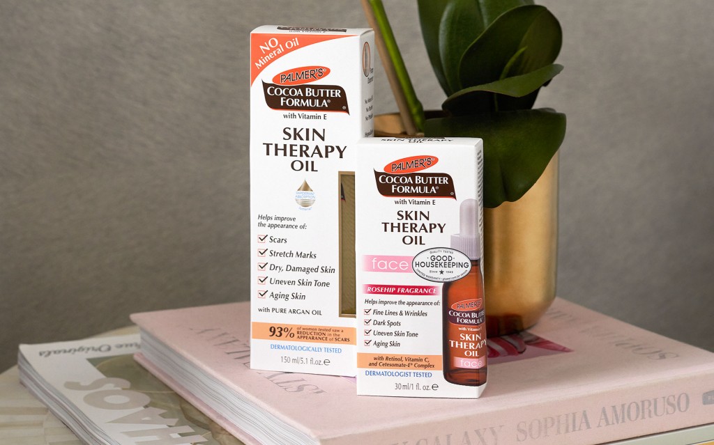 Palmer's Skin Therapy Oil and Skin Therapy Face Oil, the best face and body oils for dry skin, on top of books with planter in background 