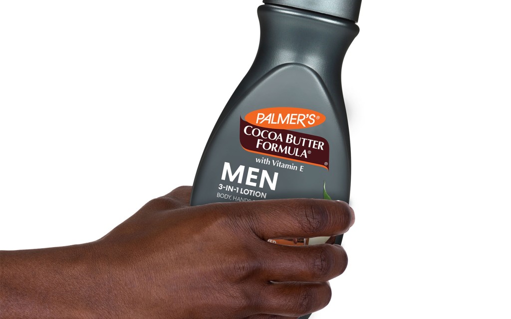 Black male's hand holding bottle of Palmer's cocoa butter for men