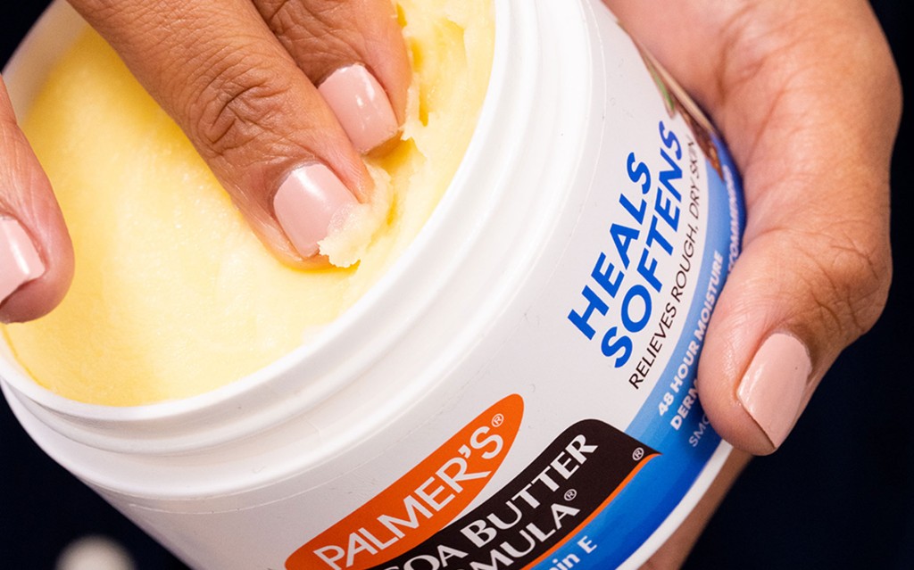 Palmer's Cocoa Butter for Sunburn being scooped out of jar by woman's hand
