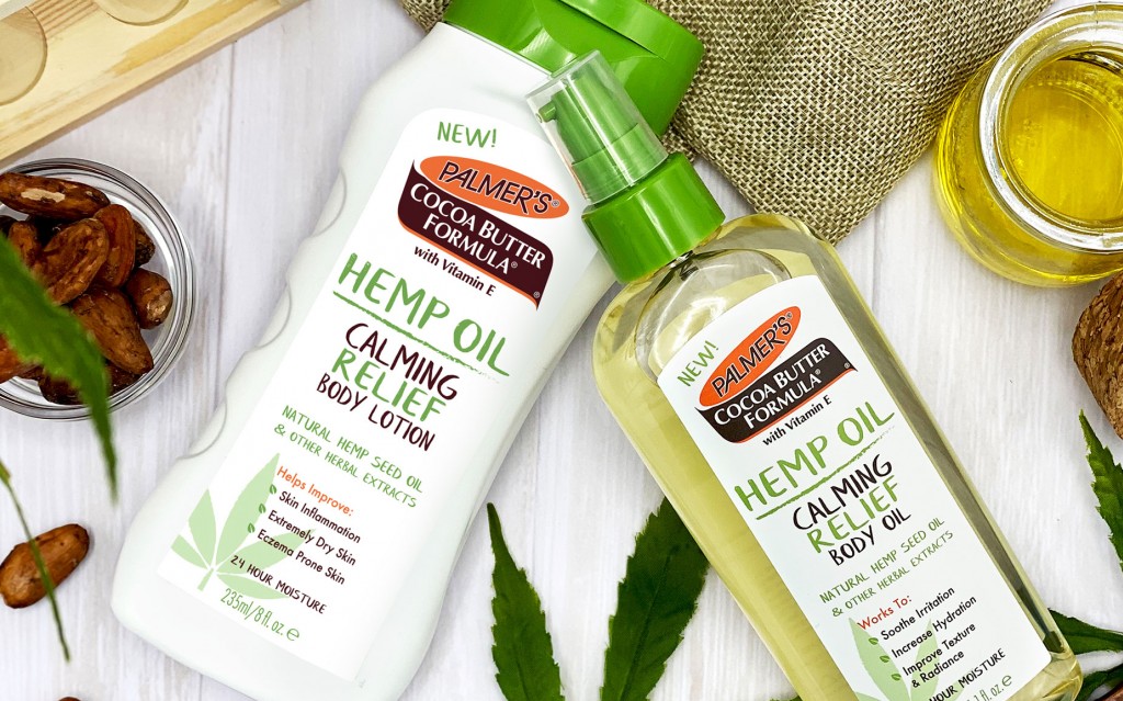 Palmer's Hemp Oil Body Lotion & Body Oil on table to cocoa beans and hemp oil and leaves