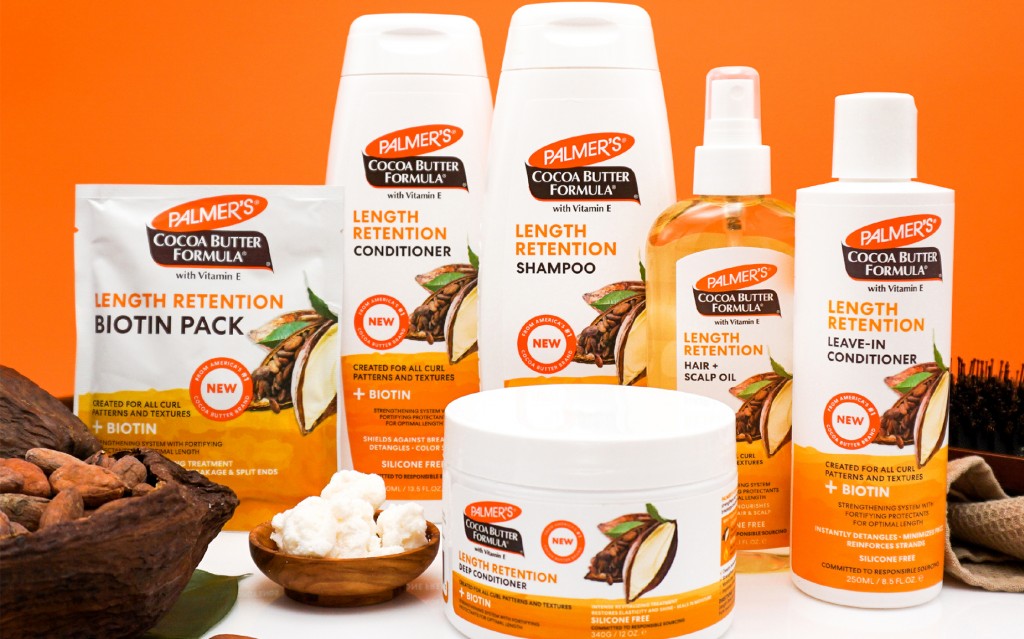 Palmer's Cocoa Butter Length Retention Hair Products on a table with ingredients against an orange background