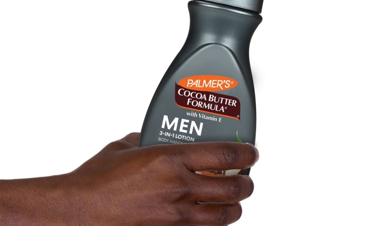 Black male's hand holding bottle of Palmer's cocoa butter for men