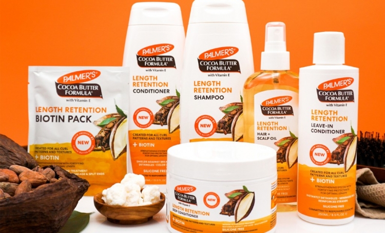 Palmer's Cocoa Butter Length Retention Hair Products on a table with ingredients against an orange background
