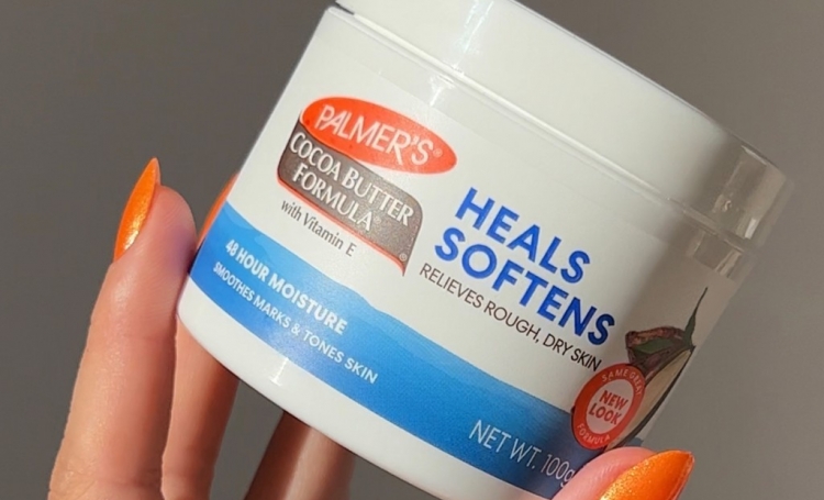 Woman's hand holding Palmer's Cocoa Butter Jar, used to heal dry skin