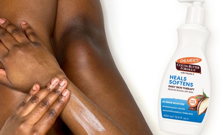 Black woman applying Palmer's Cocoa Butter Formula Lotion, an ideal option of what to put on after shaving or waxing